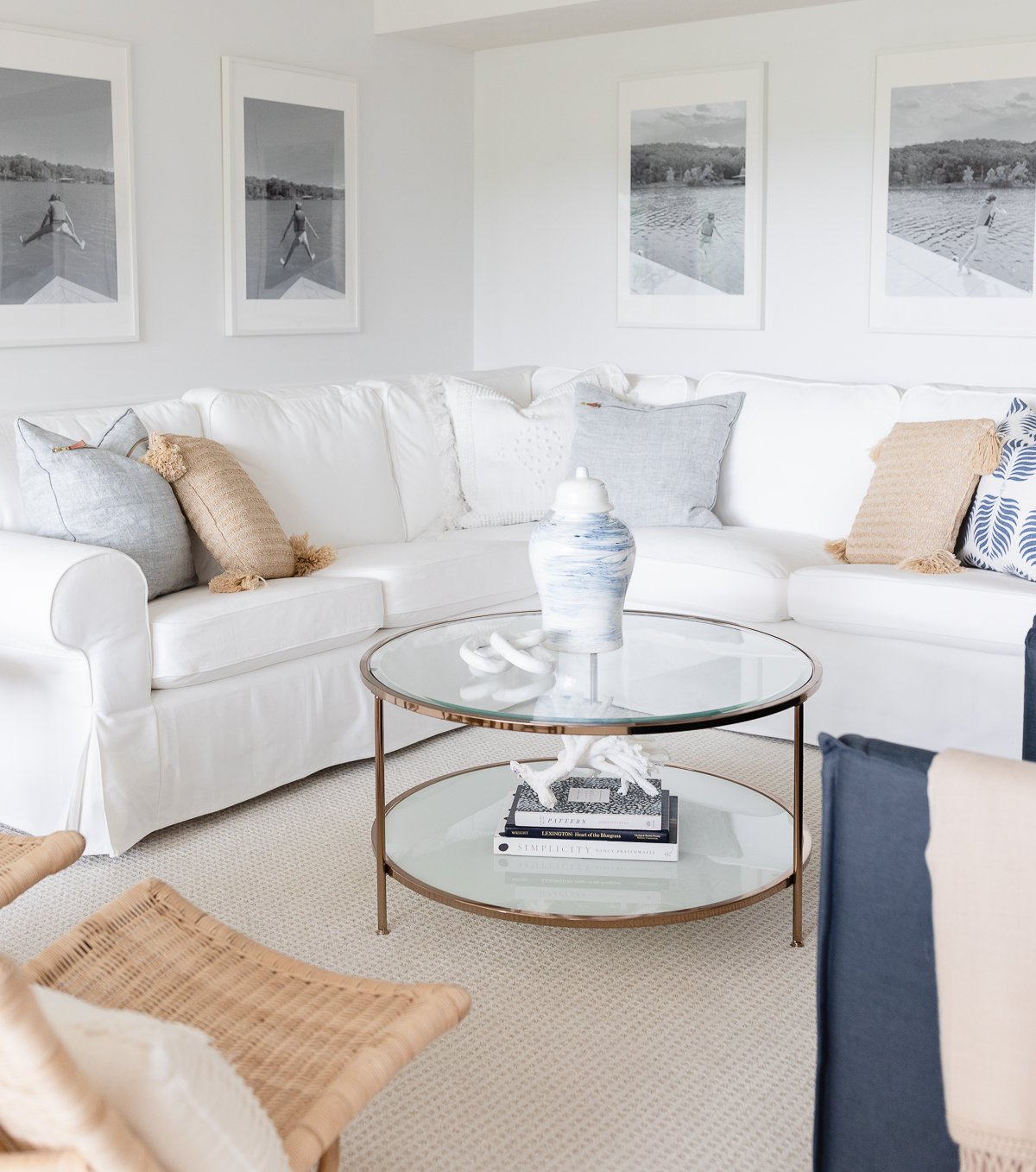 A white living room with a wall of windows, two navy blue chairs and a white sectional sofa.