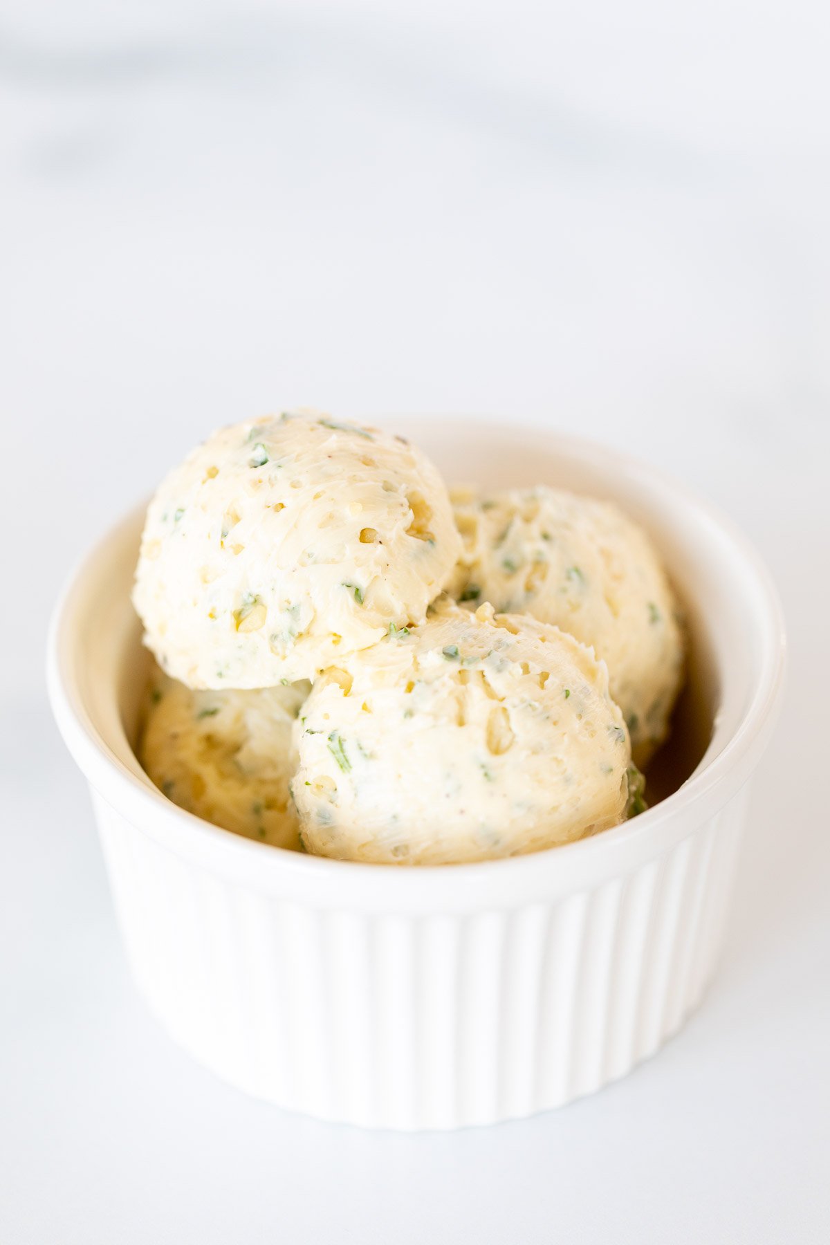 Scoops of herbed steak butter inside a white bowl.
