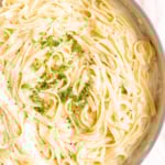 A close-up of creamy fettuccine Alfredo, made from a classic fettuccine Alfredo recipe, topped with chopped parsley and sprinkled with black pepper.