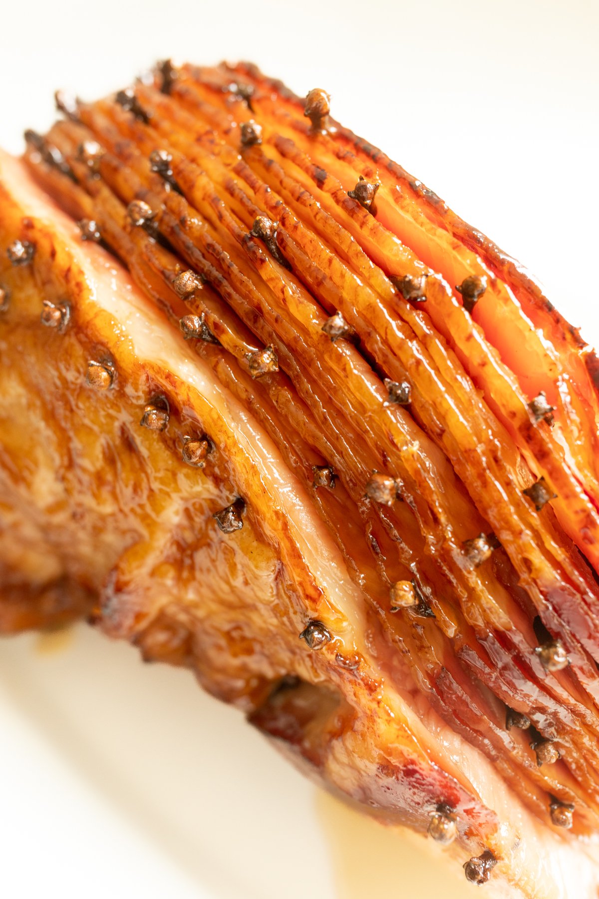 A sliced honey glazed ham studded with cloves.