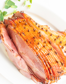 honey glazed ham garnished with fresh pansies on a white platter