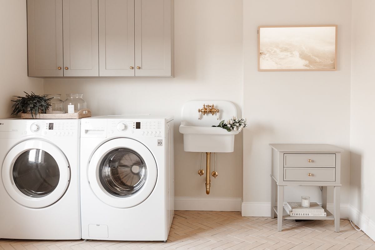 a laundry room with greige cabinetry and a wall sink