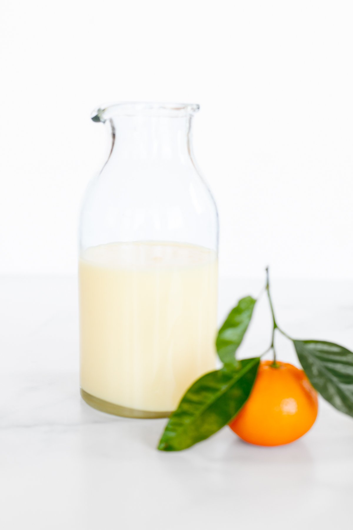 A glass bottle of orange glaze, with a small orange beside it