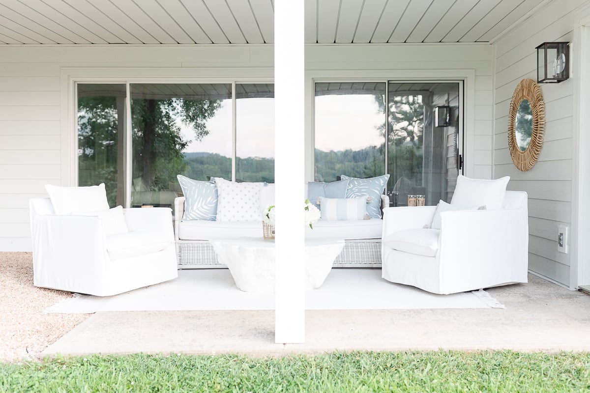 A porch with white furniture and a glass door featuring underdecking.