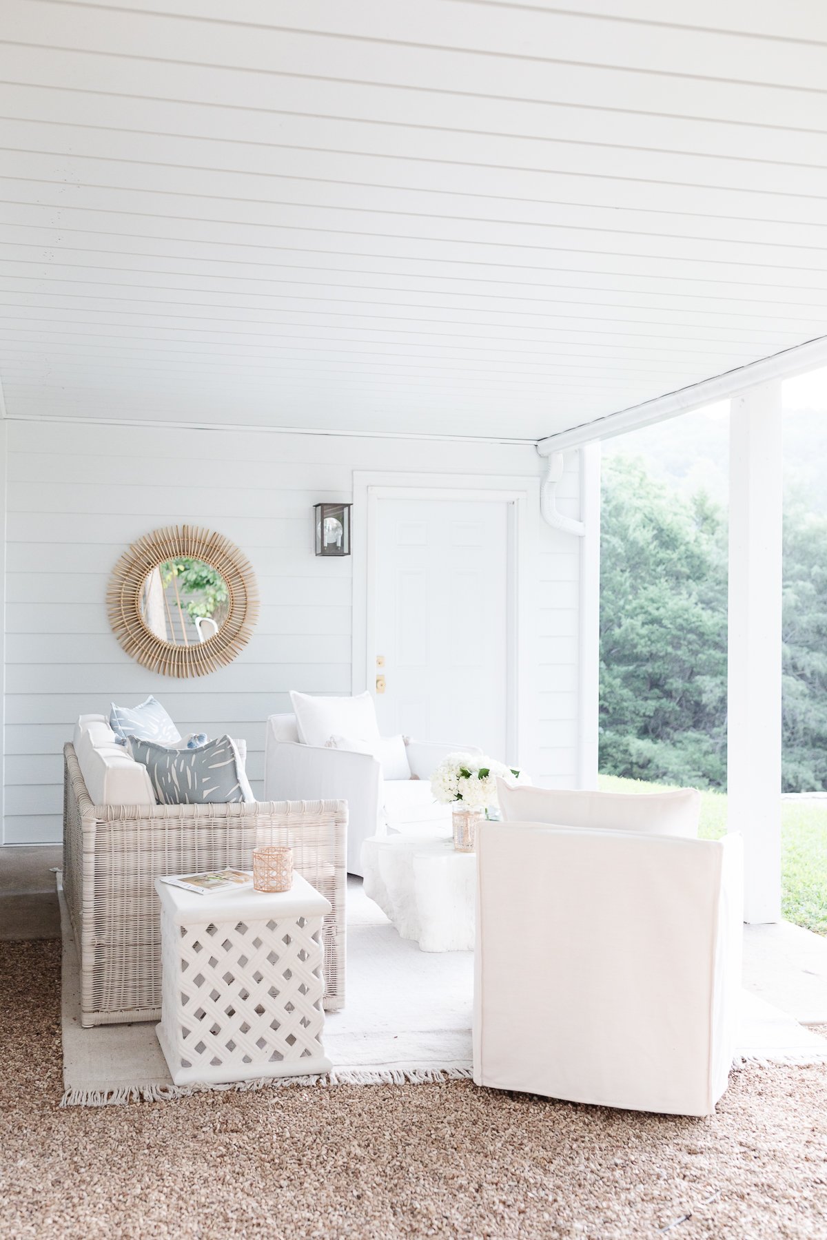 A covered porch with wicker furniture and an under deck drainage system.