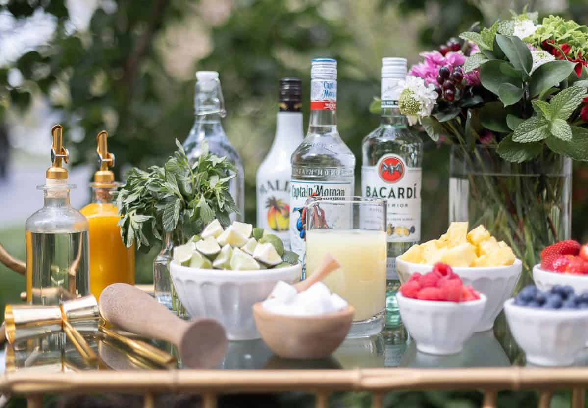 An at-home mojito bar cart with a variety of the best rums for mojitos in the background.