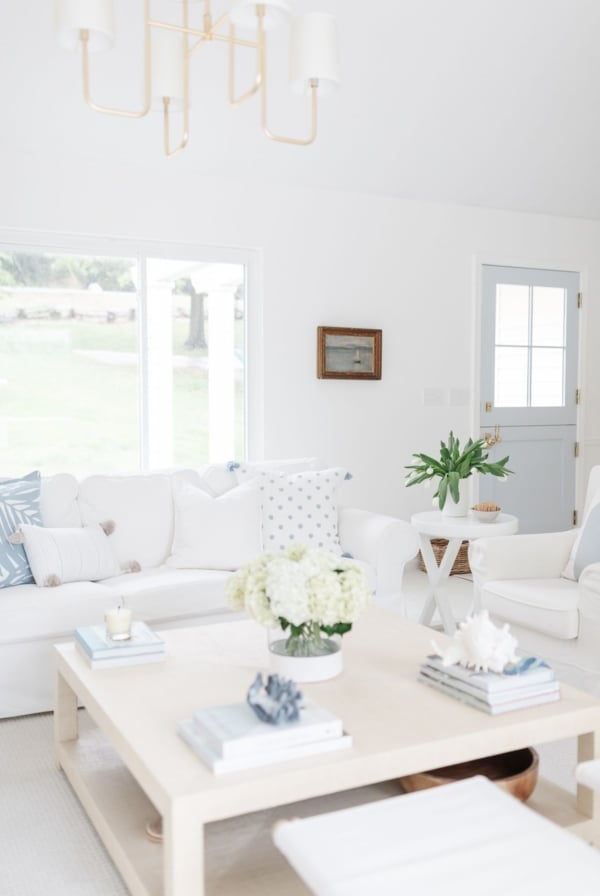 A coastal modern living room with white furniture and brass lighting