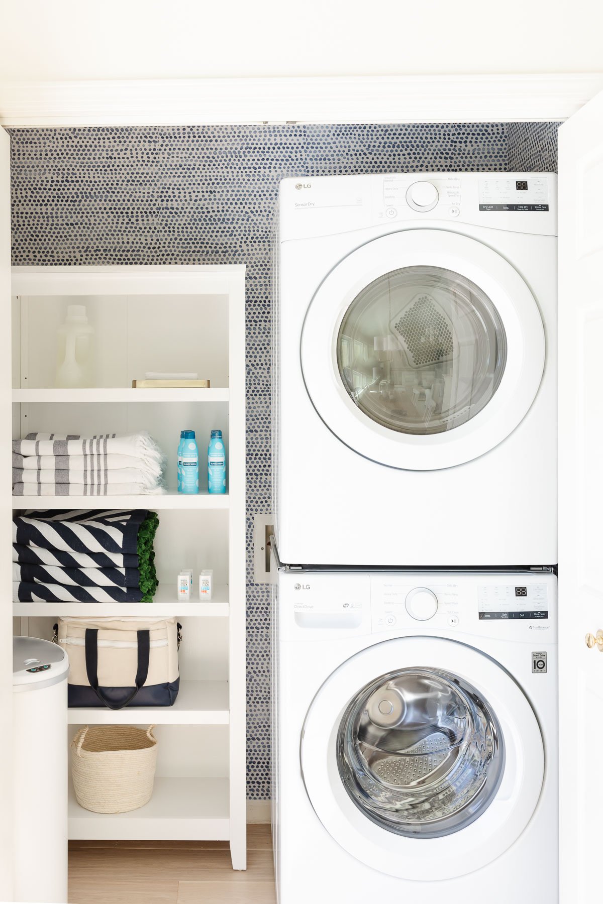 bookcase trashcan and stacked washer and dryers in closet