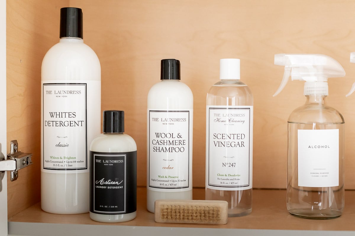 Various bottles of cleaning products sit on a laundry room shelf.