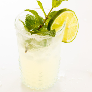 A mint margarita in a clear glass on a white surface