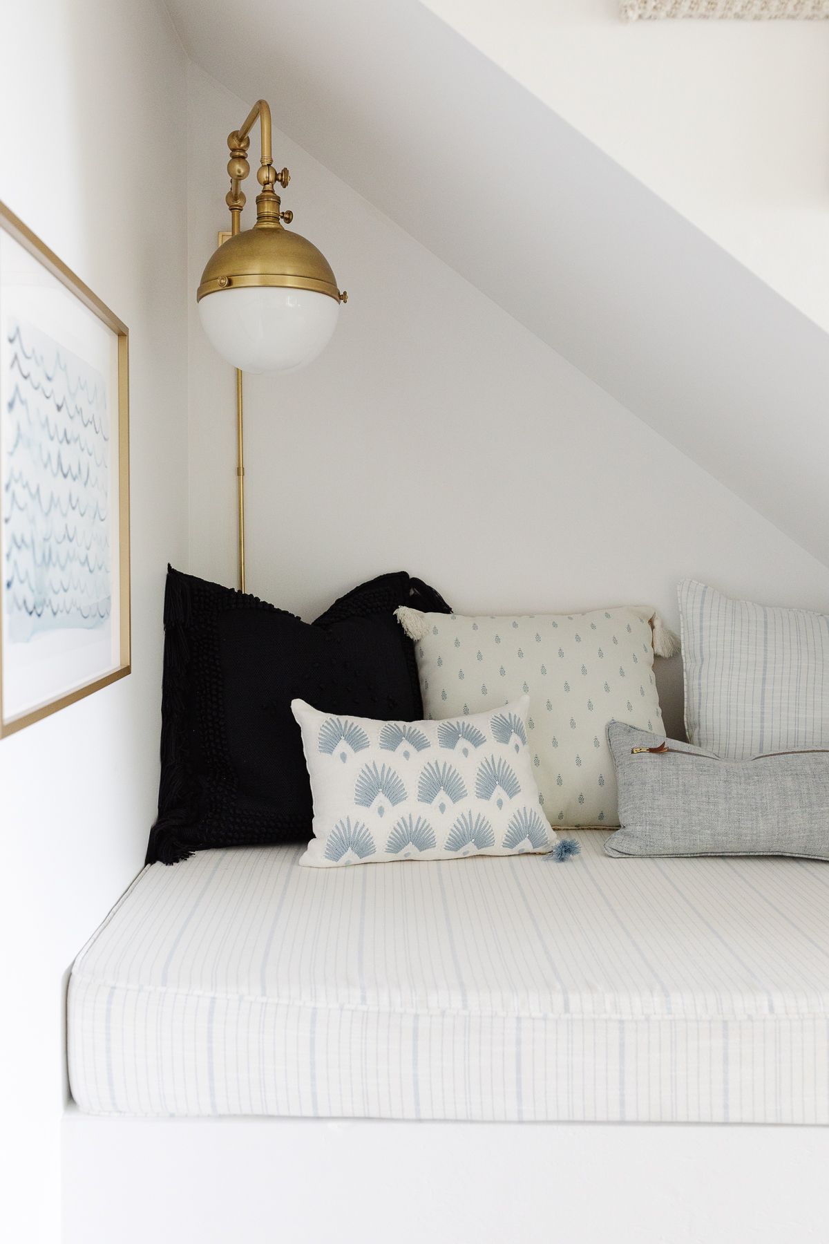 A reading nook under a staircase with coastal modern style and a brass nautical light