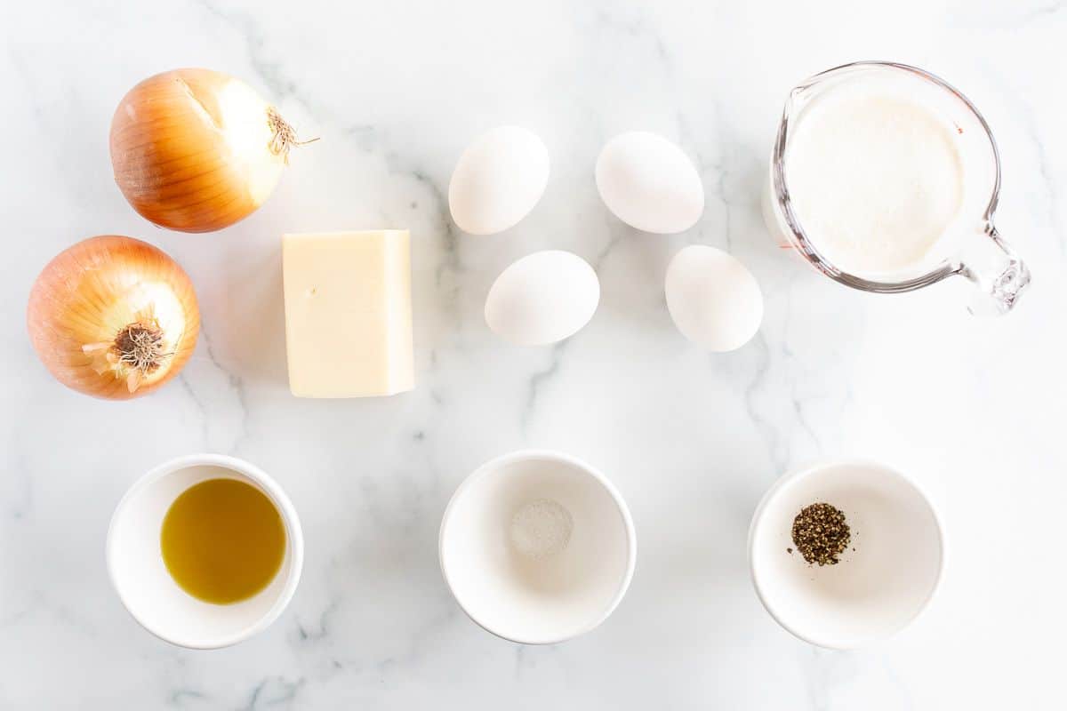 Onion quiche ingredients laid out on a marble surface.