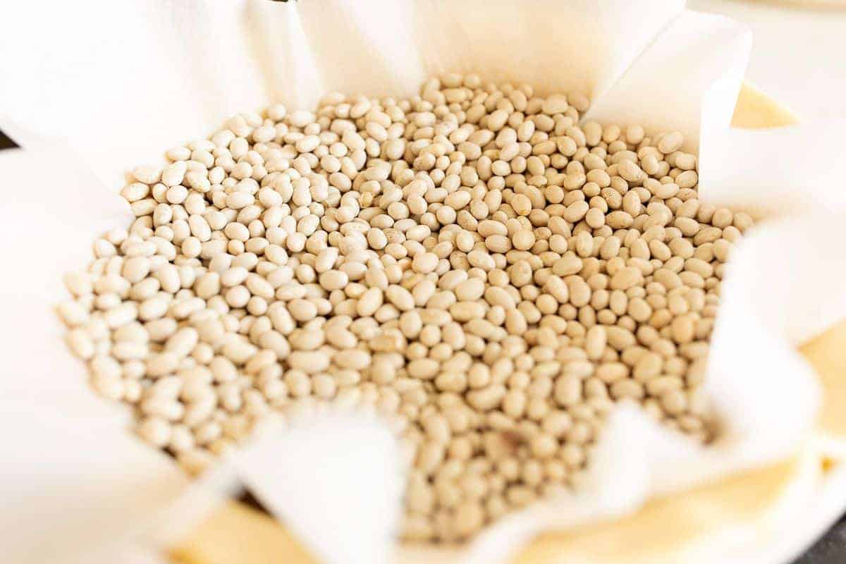 A blind baked crust process shot, crust lined with parchment and filled with beans for weight.