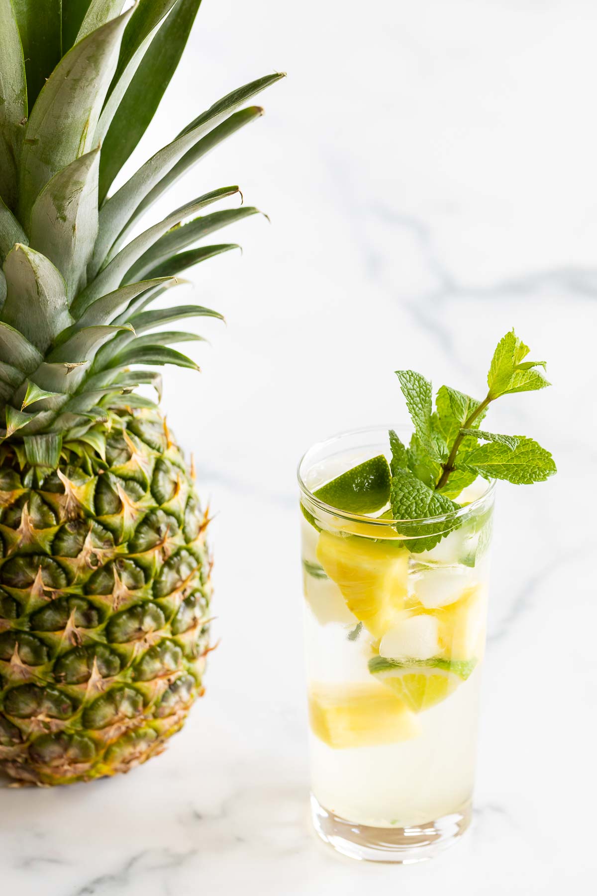 pineapple mojito in highball glass with a pineapple next to it