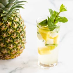 pineapple mojito in highball glass with a pineapple next to it