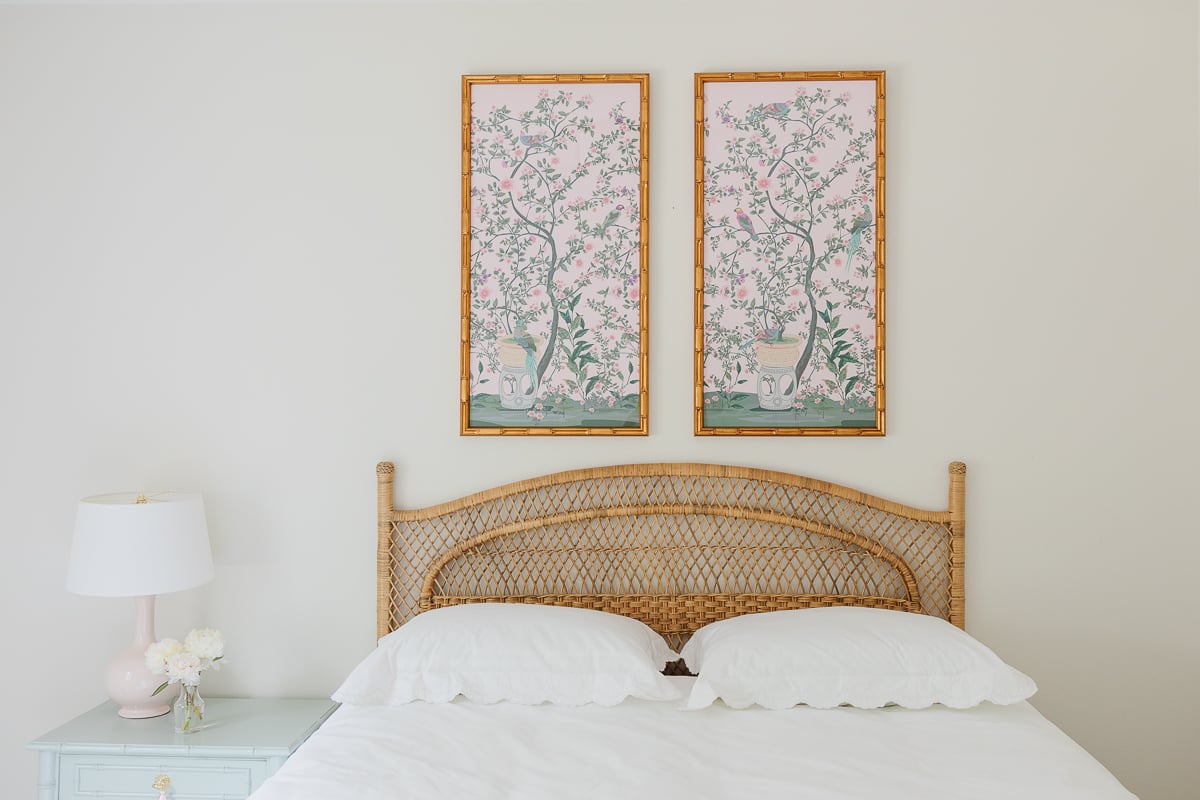 A bedroom with a rattan bed and two paintings on the wall.