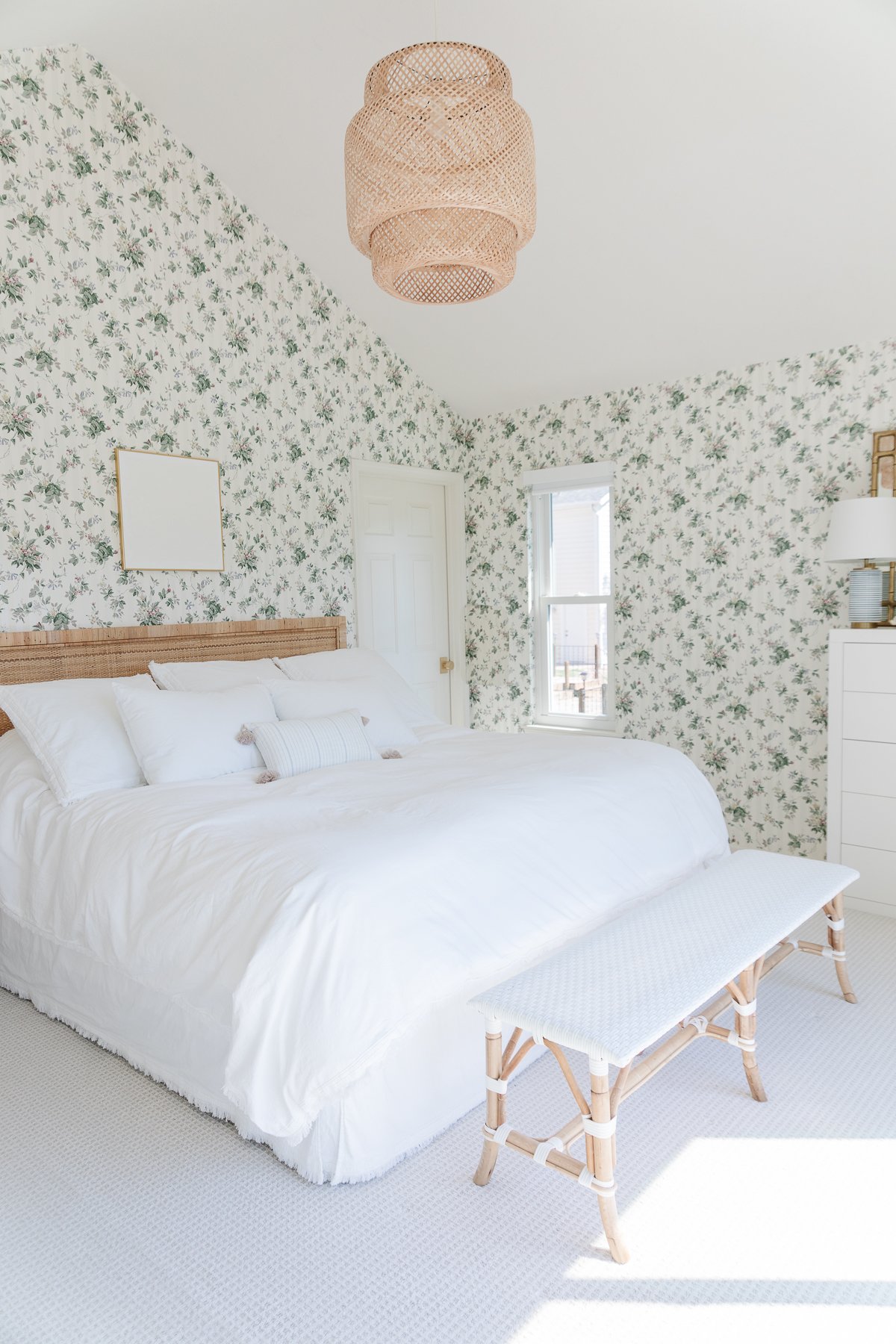 A Rattan Bed in a bedroom with floral wallpaper.