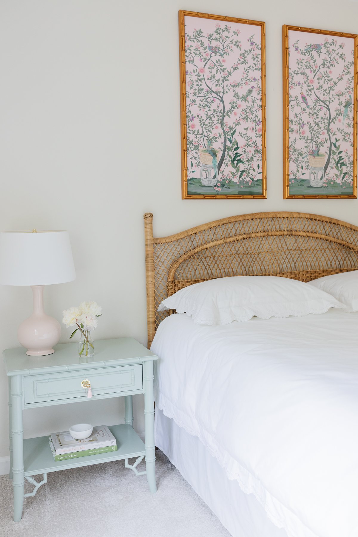 A rattan bed in a room with two paintings on the wall.