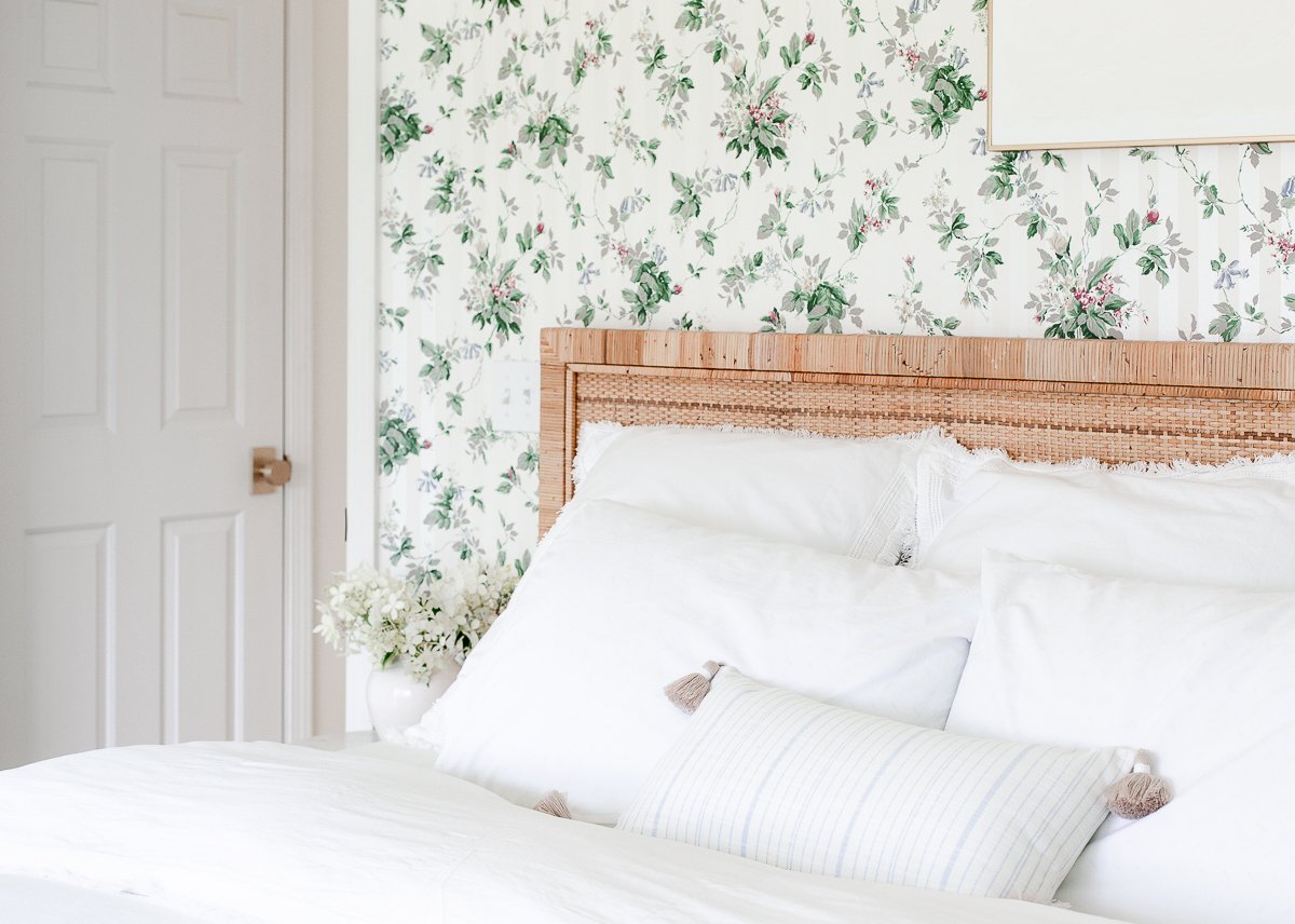 A Rattan Bed in a bedroom with floral wallpaper.