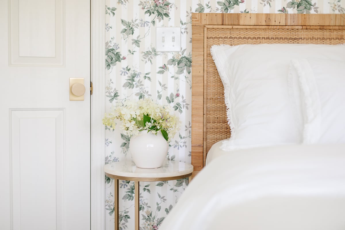 A Rattan Bed in a bedroom with floral wallpaper.