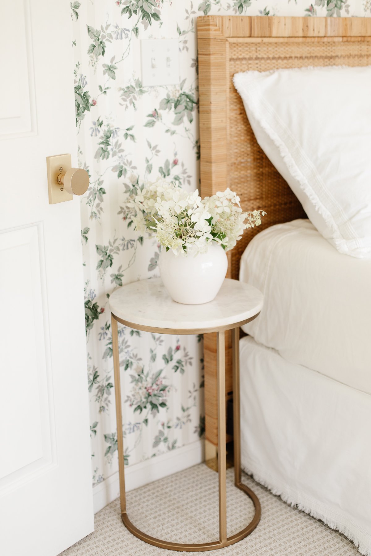 A Rattan Bed in a bedroom with floral wallpaper.