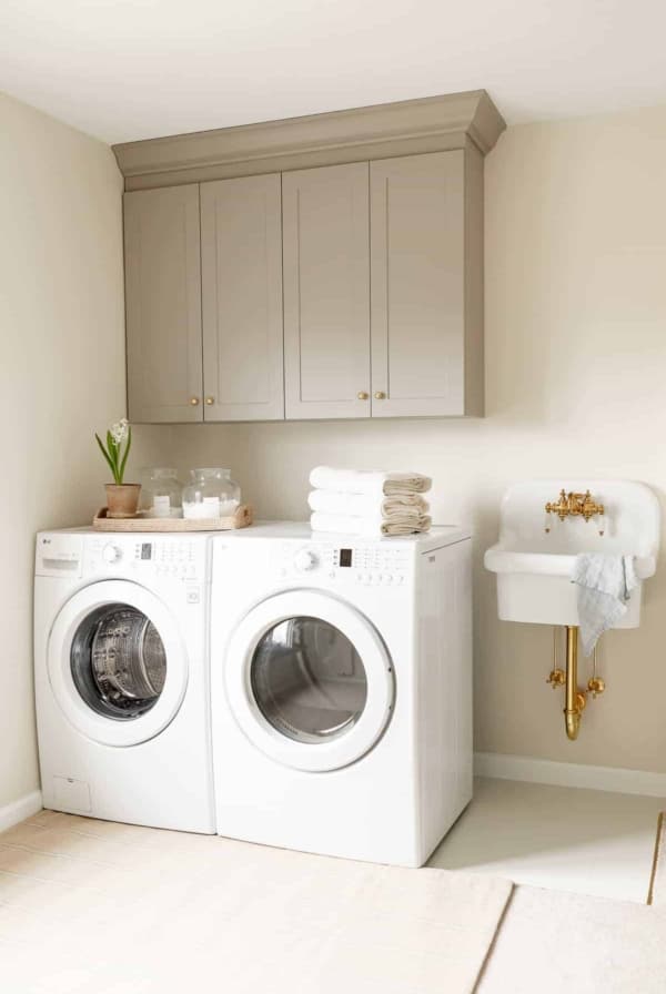 A second floor laundry room with gray cabinets and a small white sink.