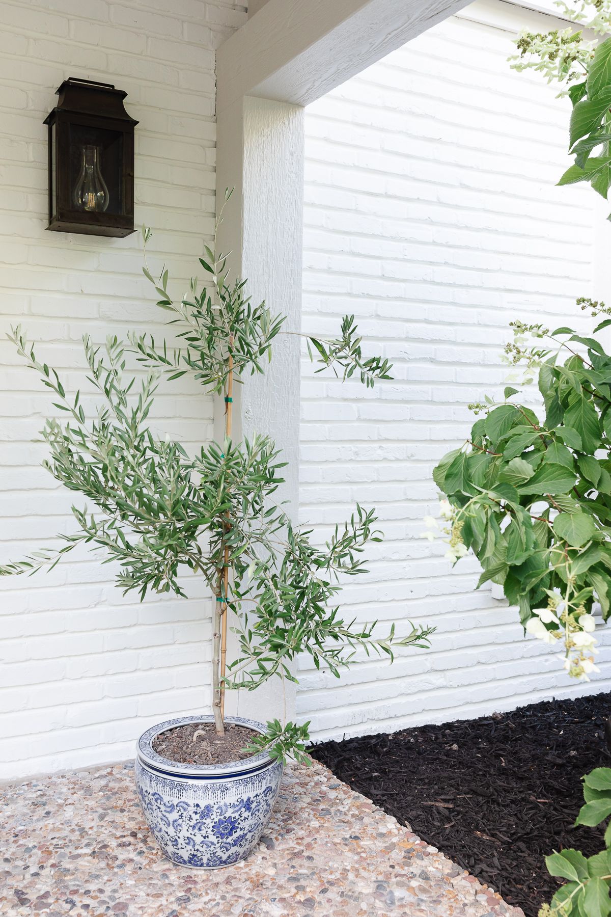 The covered porch of a tudor home, with brick painted in Benjamin Moore Swiss Coffee.