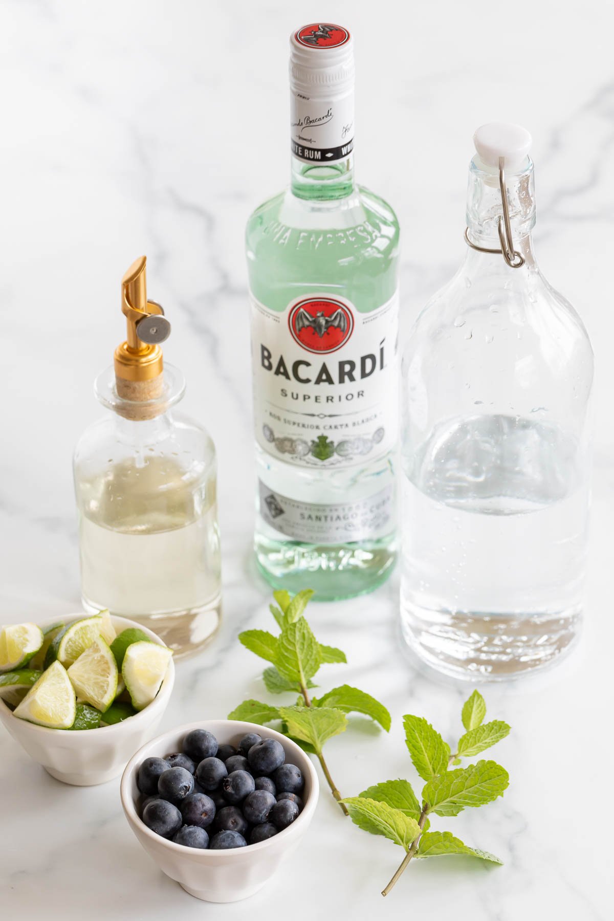 Ingredients for a blueberry mojito on a marble countertop