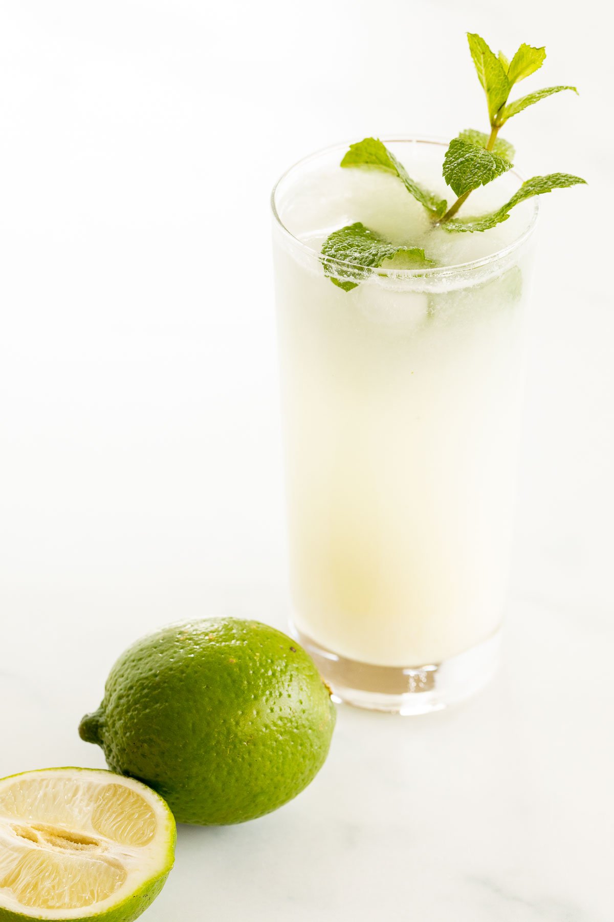 A coconut mojito garnished with mint on a marble surface.