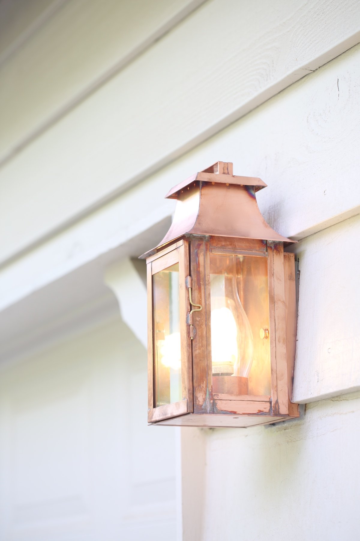 A copper lantern on the white painted exterior of a home.