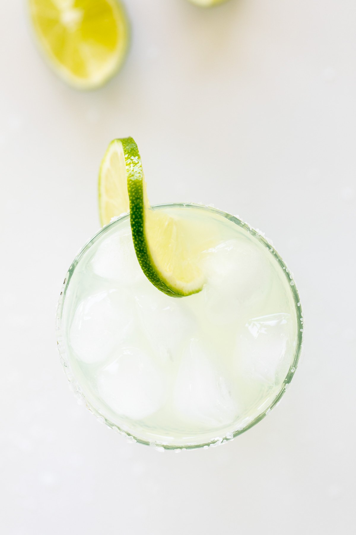 A homemade margarita recipe served up in clear glasses with limes