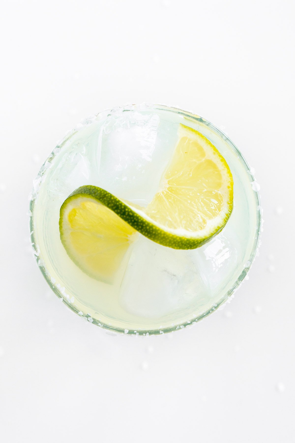 A homemade margarita recipe served up in clear glasses with limes