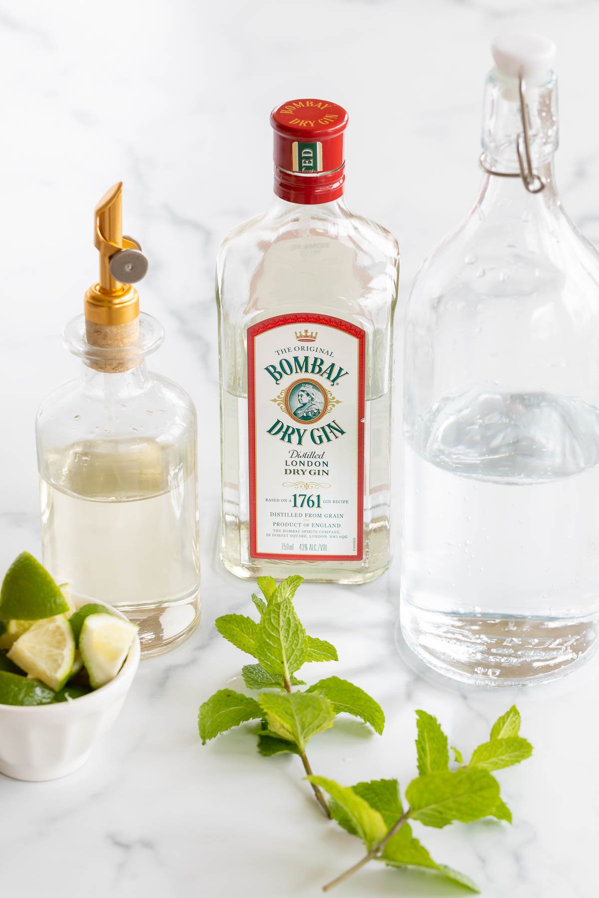 Ingredients for a gin mojito on a marble countertop.