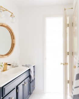 A nautical inspired bathroom with white walls and a wood vanity painted in Benjamin Moore Hale Navy paint color.