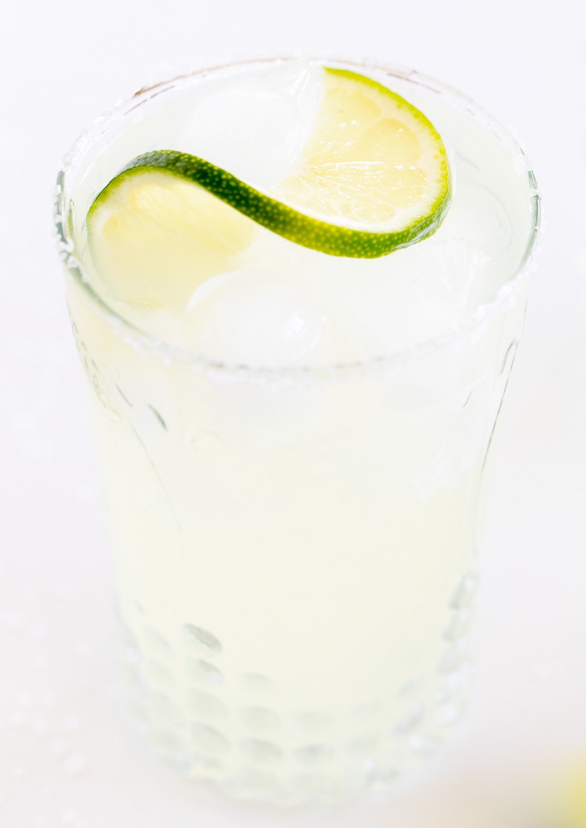 A homemade margarita recipe served up in clear glasses with limes