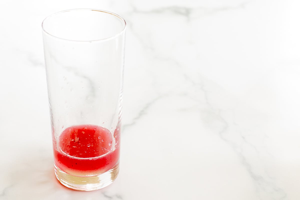 Pink liquid in the bottom of a clear glass.