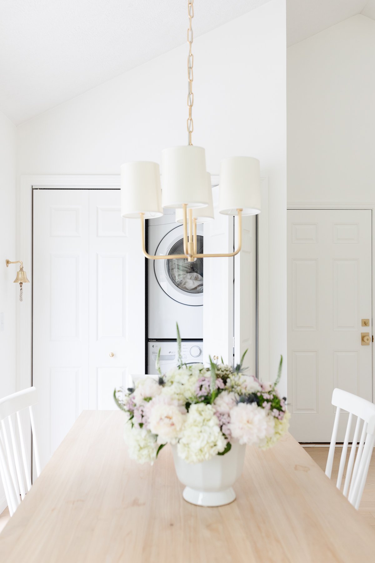 A white dining room with a white table and chairs, perfect for laundry closet ideas.