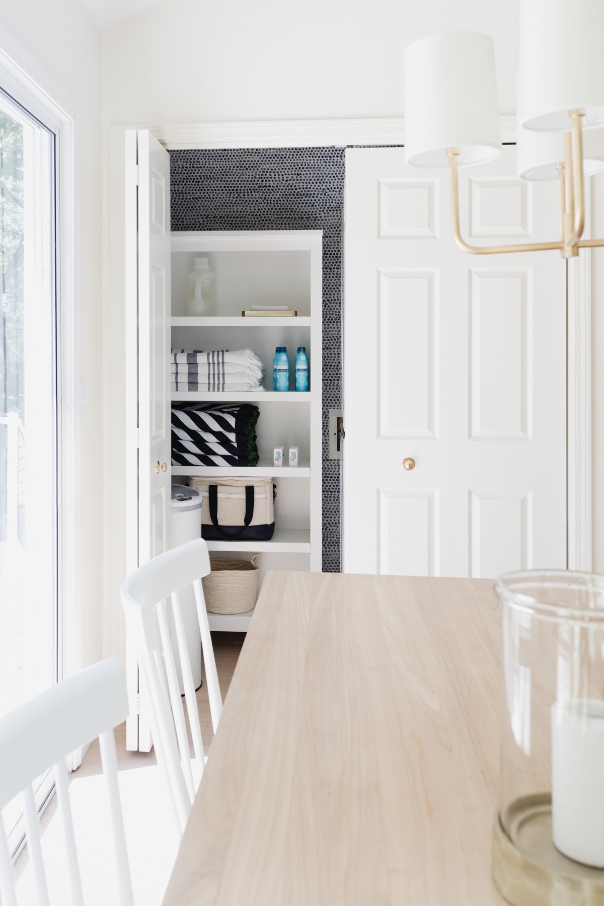 A white dining room with a white table and chairs, featuring a laundry closet.