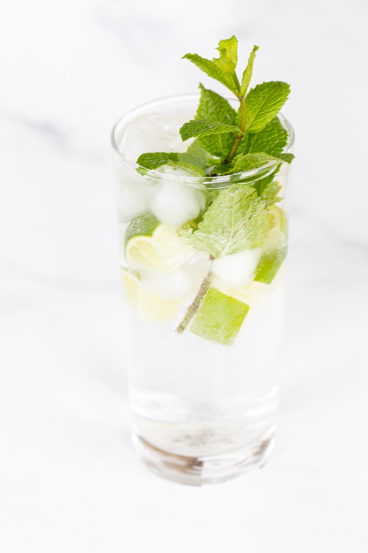 A clear glass full of a virgin mojito recipe on a marble surface.