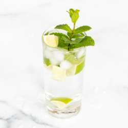 A clear glass full of a virgin mojito recipe on a marble surface.