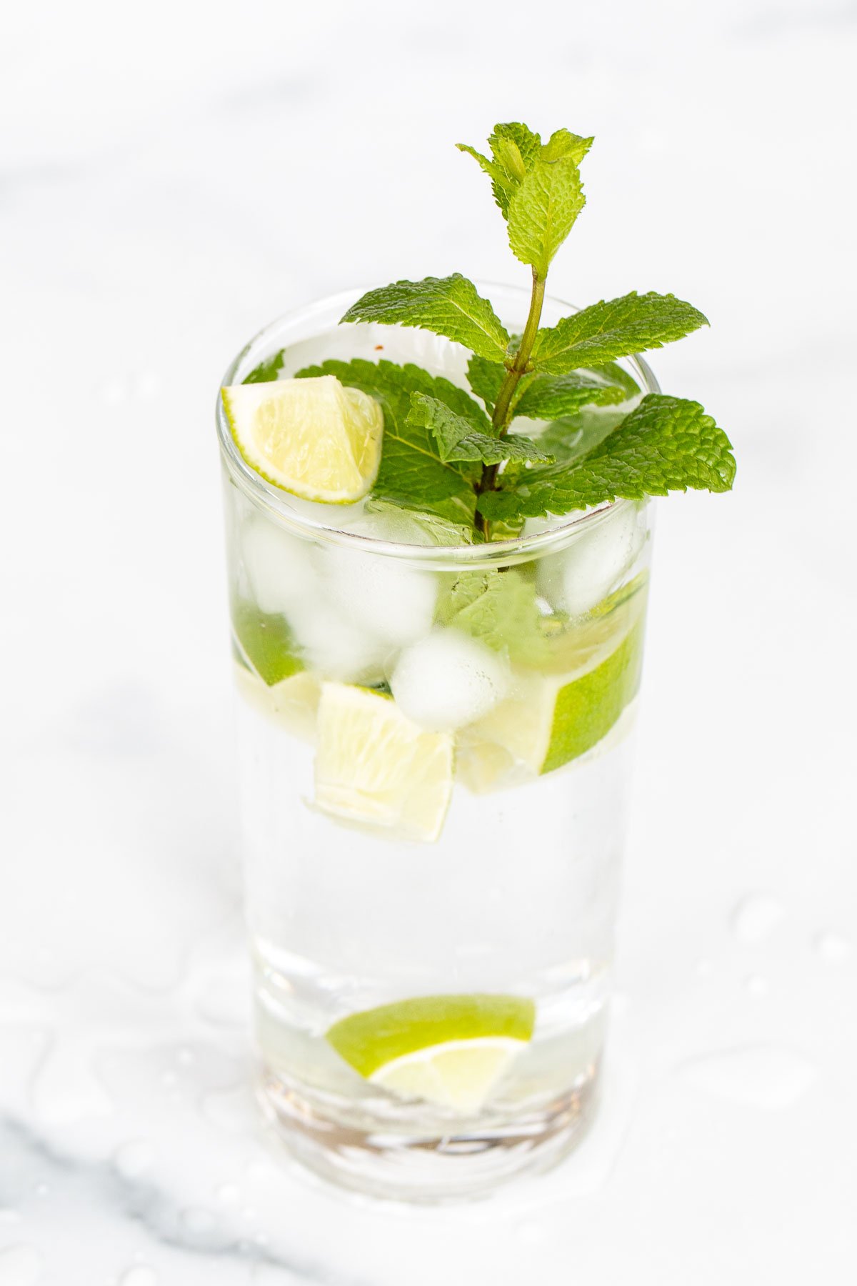 A clear glass full of a virgin mojito recipe on a marble surface.