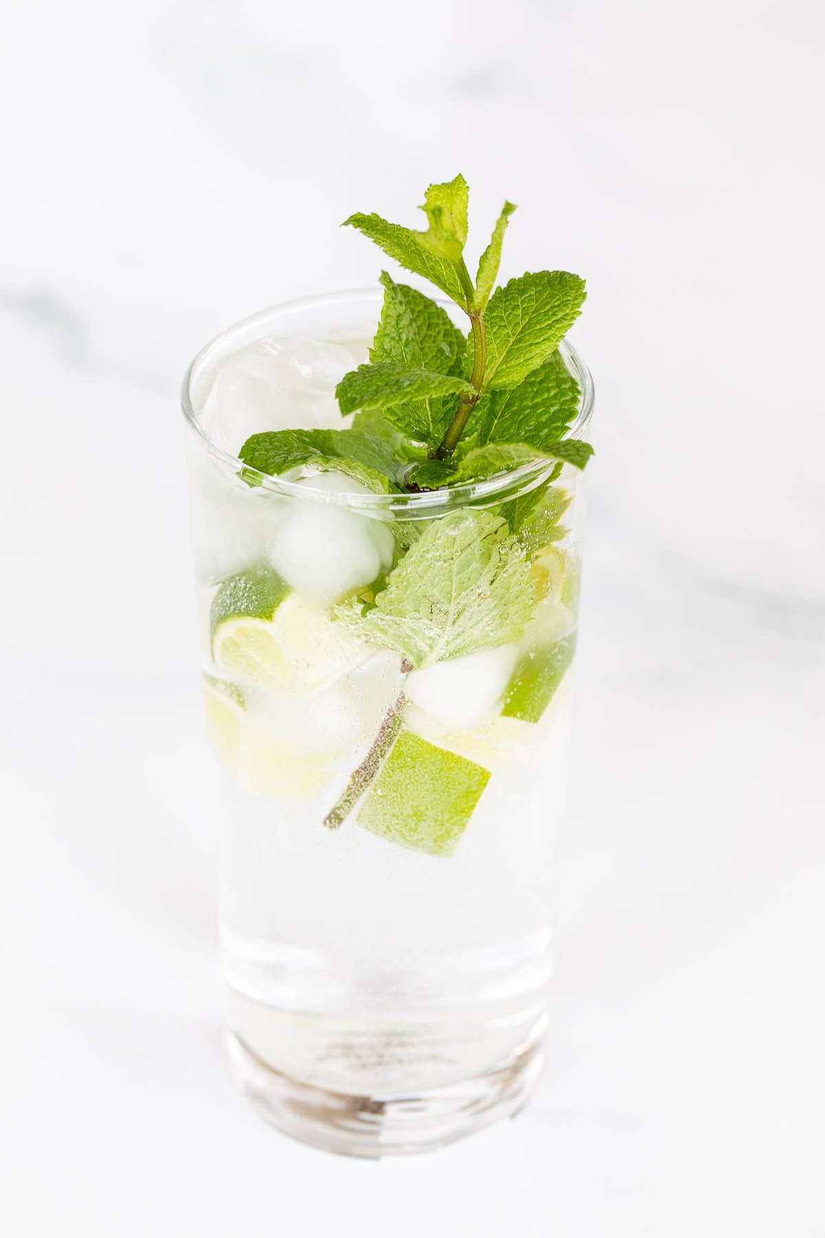 A clear glass full of a virgin mojito recipe on a marble surface.