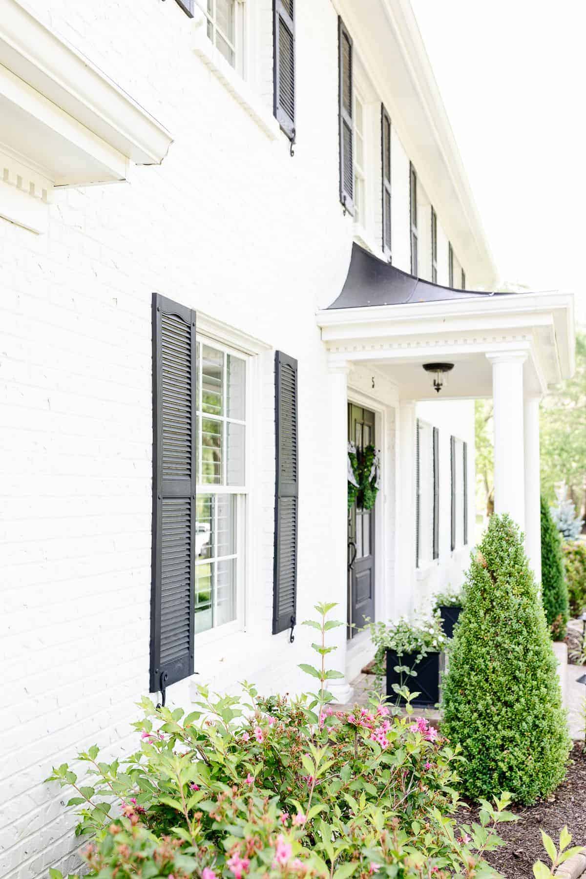 A white brick house with black shutters.