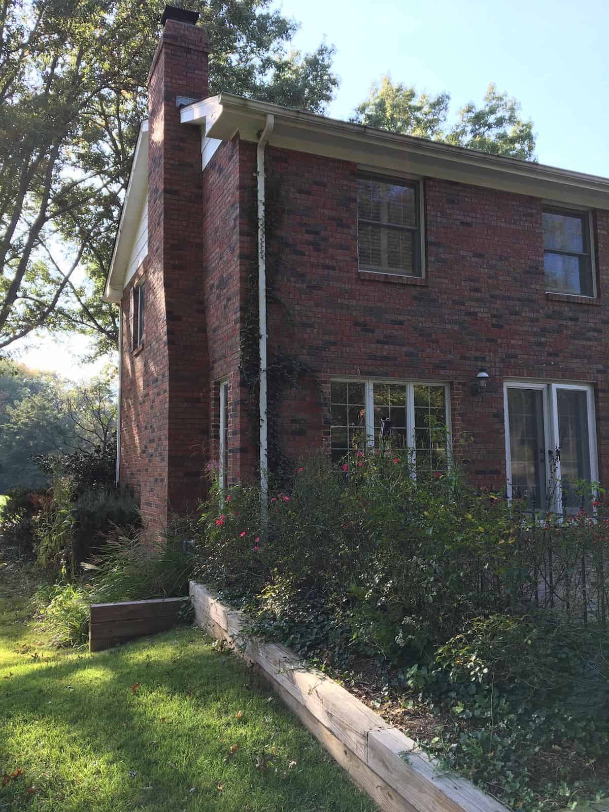 A dark brick house exterior before undergoing a paint transformation.