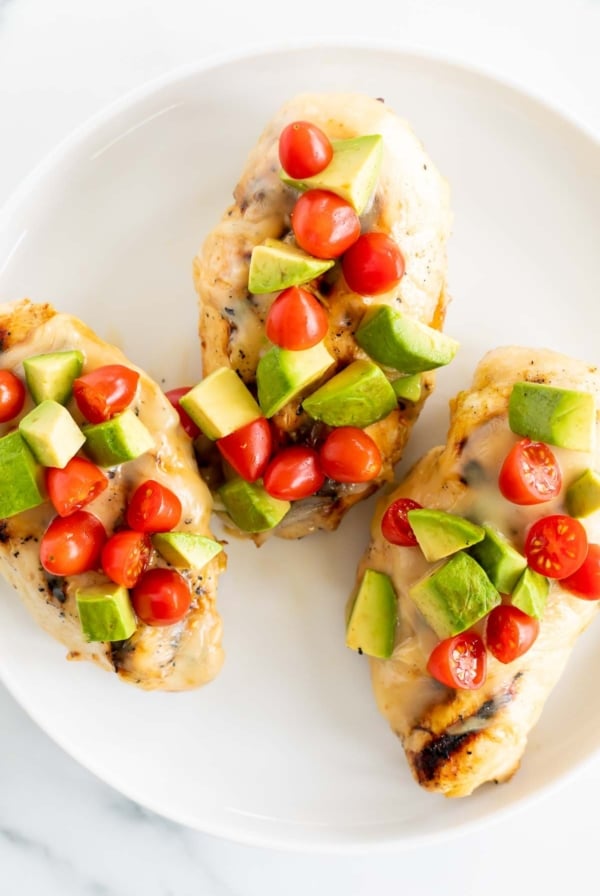 California chicken grill on a white plate, topped with diced avocado and tomato.