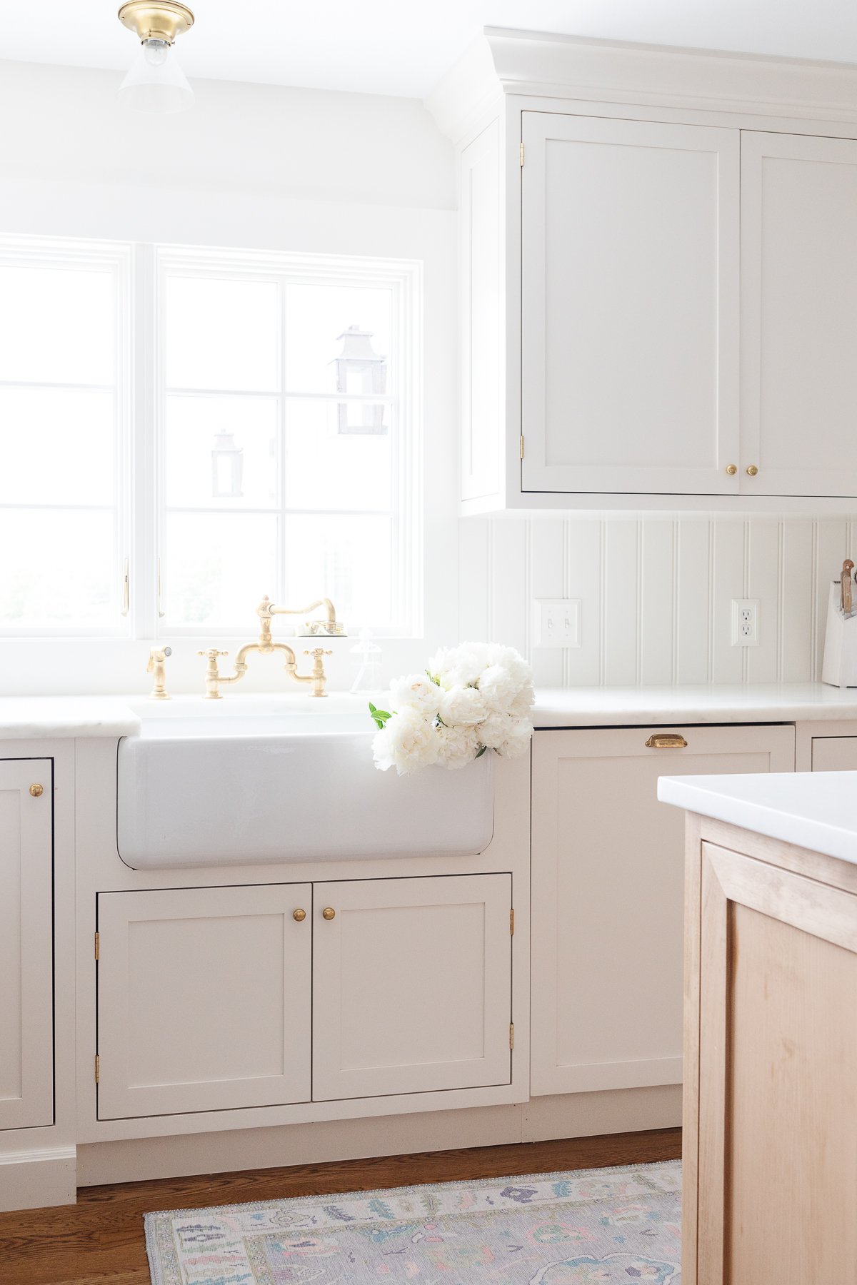 A kitchen with white custom cabinetry and a white sink.