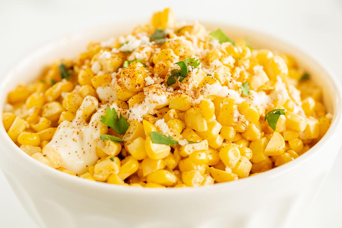 A white bowl of esquites (Mexican street corn salad).