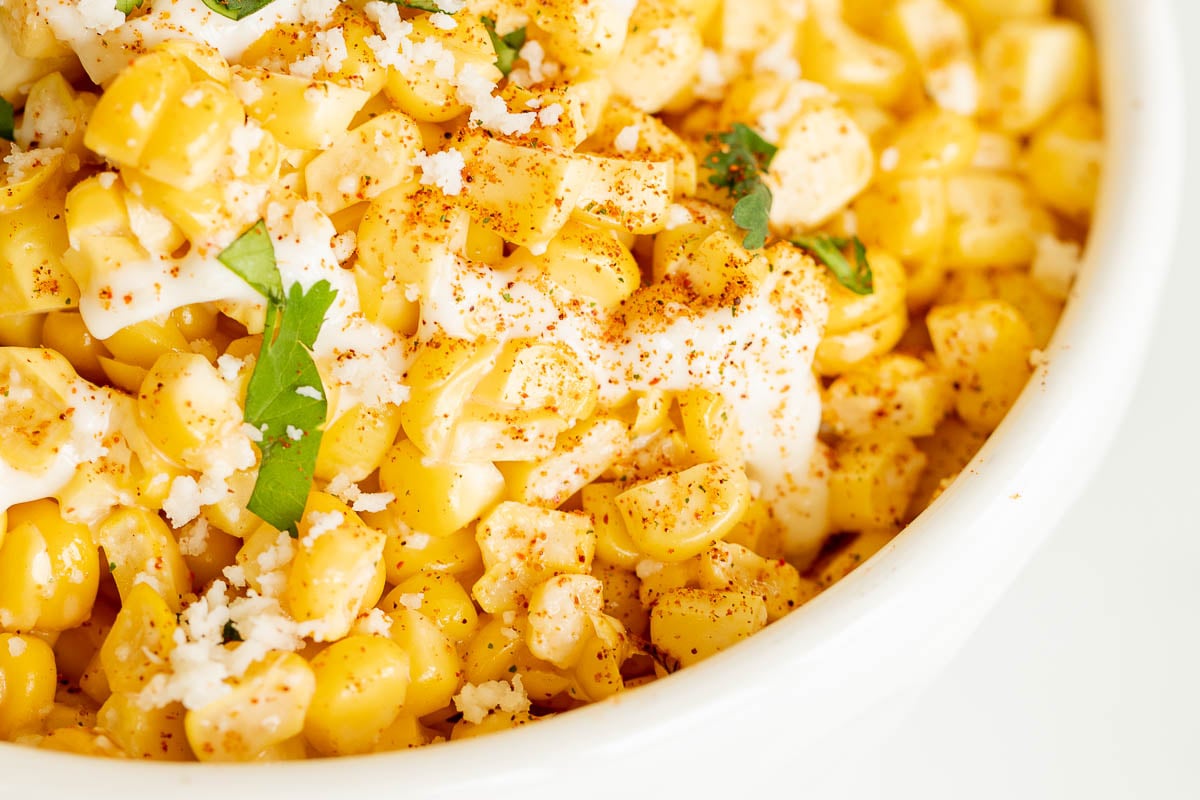 A white bowl of esquites (Mexican street corn salad).