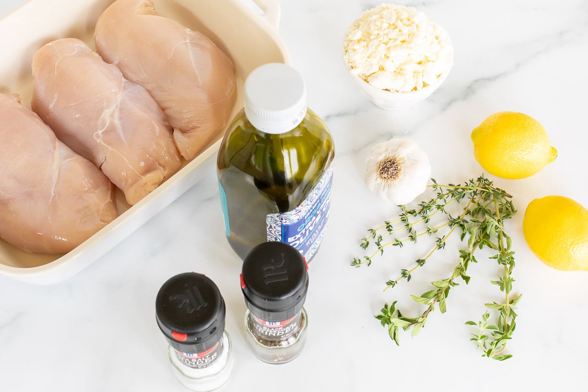 Ingredients for Greek chicken spread out on a white countertop. 