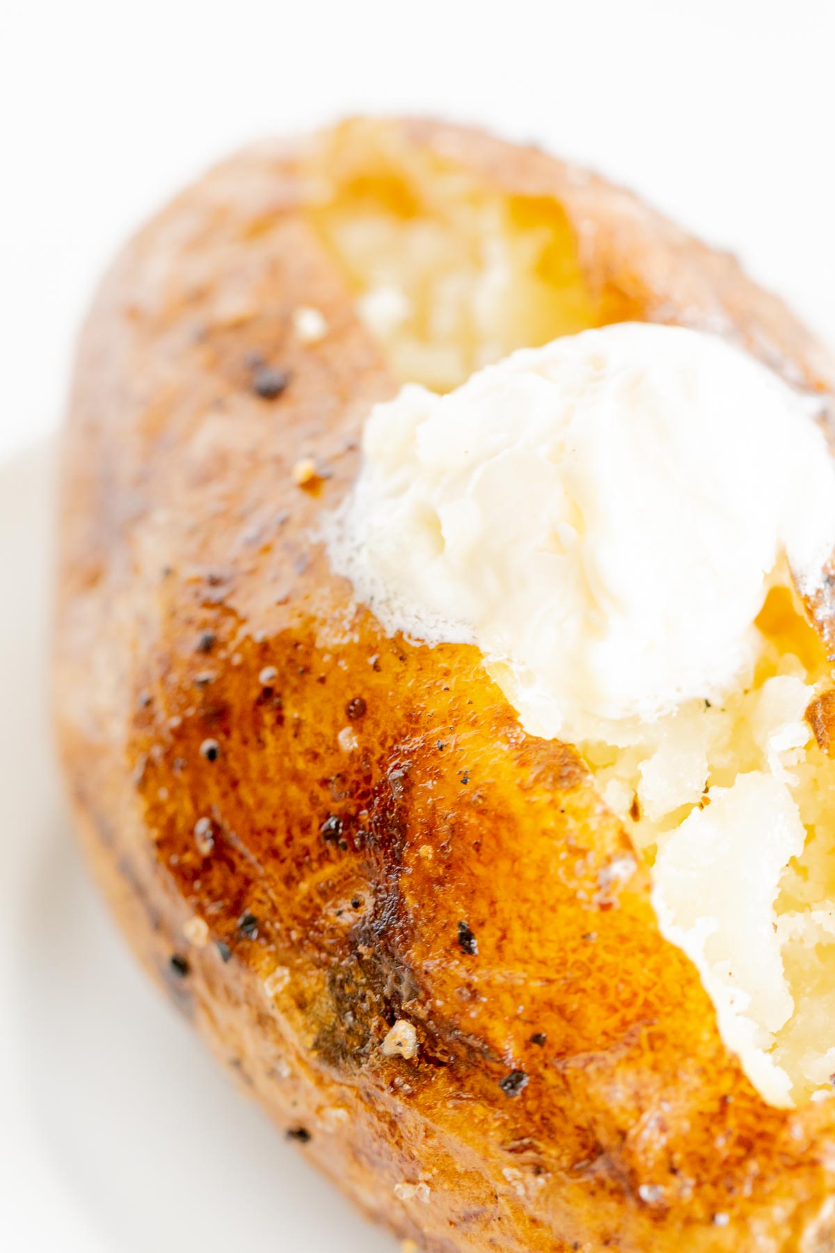 A grilled baked potato on a white plate.